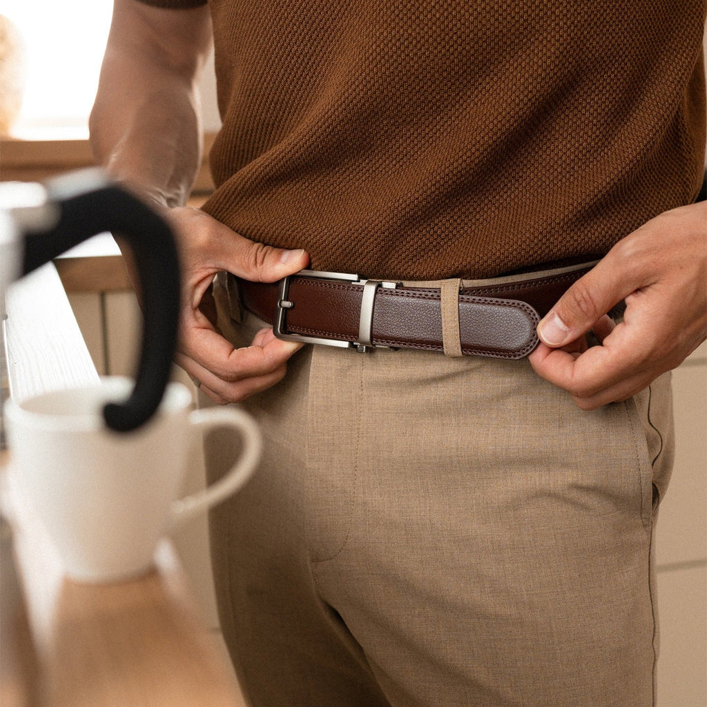 Person adjusting a brown belt with a silver buckle in a casual setting.
