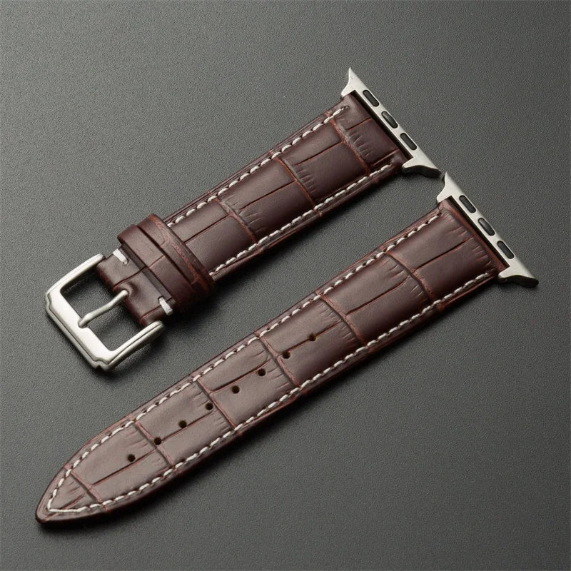 Brown leather watch strap with silver buckle on a gray background