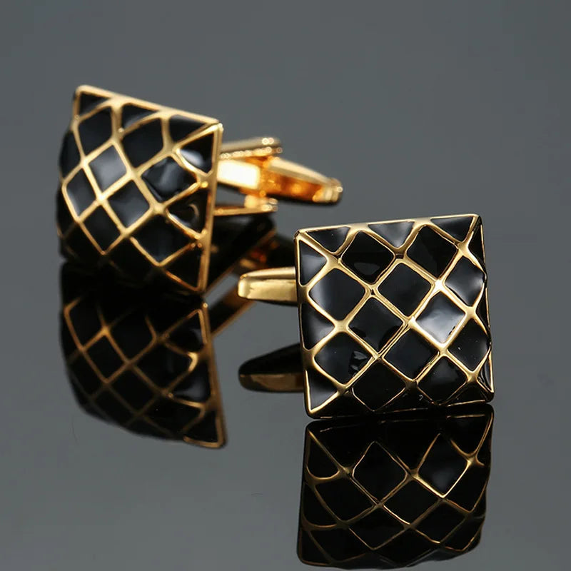 Black and gold geometric cufflinks on a reflective surface with a dark background