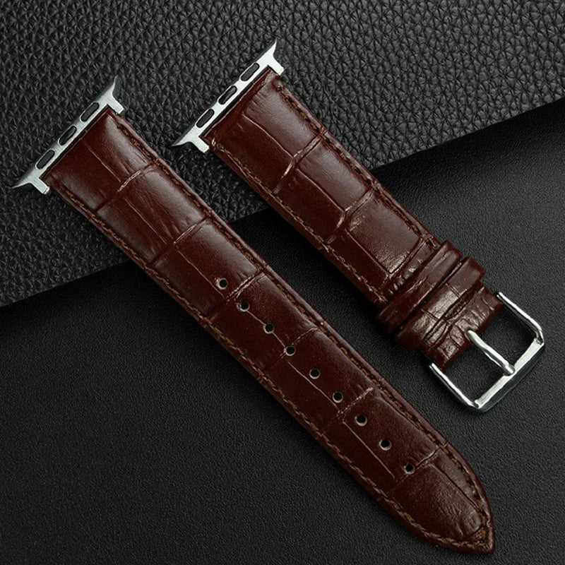 Brown leather watch strap with silver buckle on a dark textured background