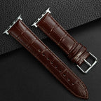 Brown leather watch strap with silver buckle on a dark textured background