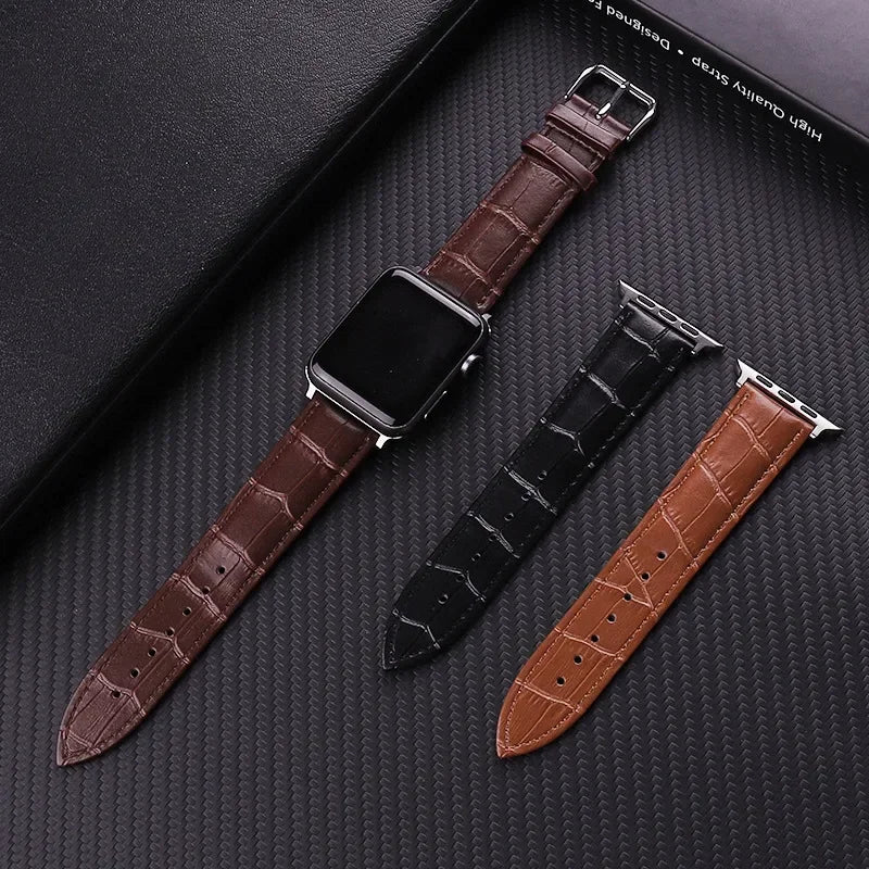 Three leather watch straps in brown, black, and another brown color on a textured dark surface.
