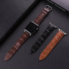 Three leather watch straps in brown, black, and another brown color on a textured dark surface.