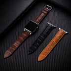 Three leather watch straps in brown, black, and tan on a dark textured surface.